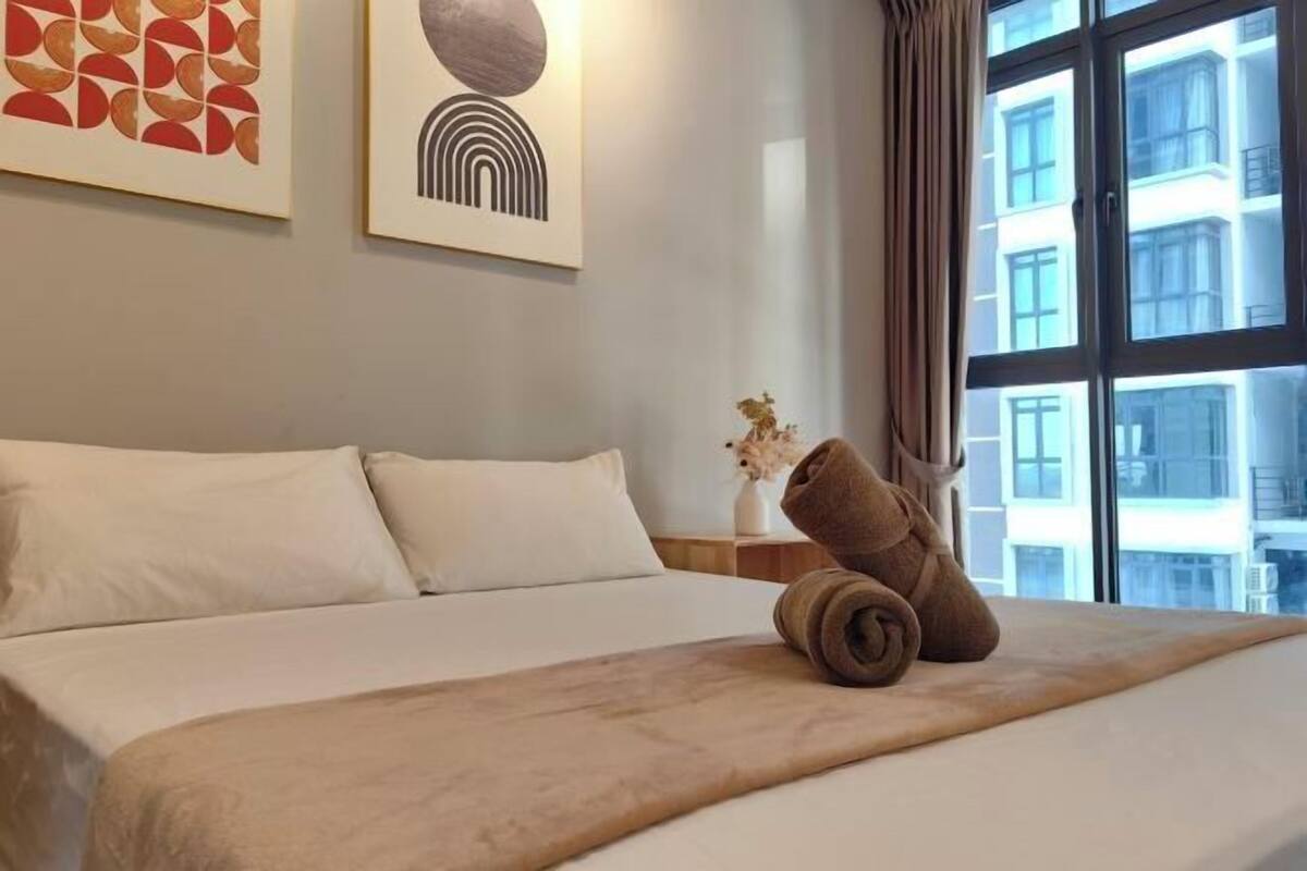A hotel room with a bed, a window with curtains, and artwork on the wall.