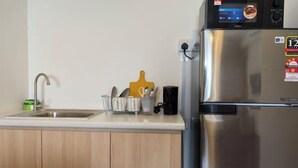 Una cucina con frigorifero in acciaio inox, lavello e portautensili.