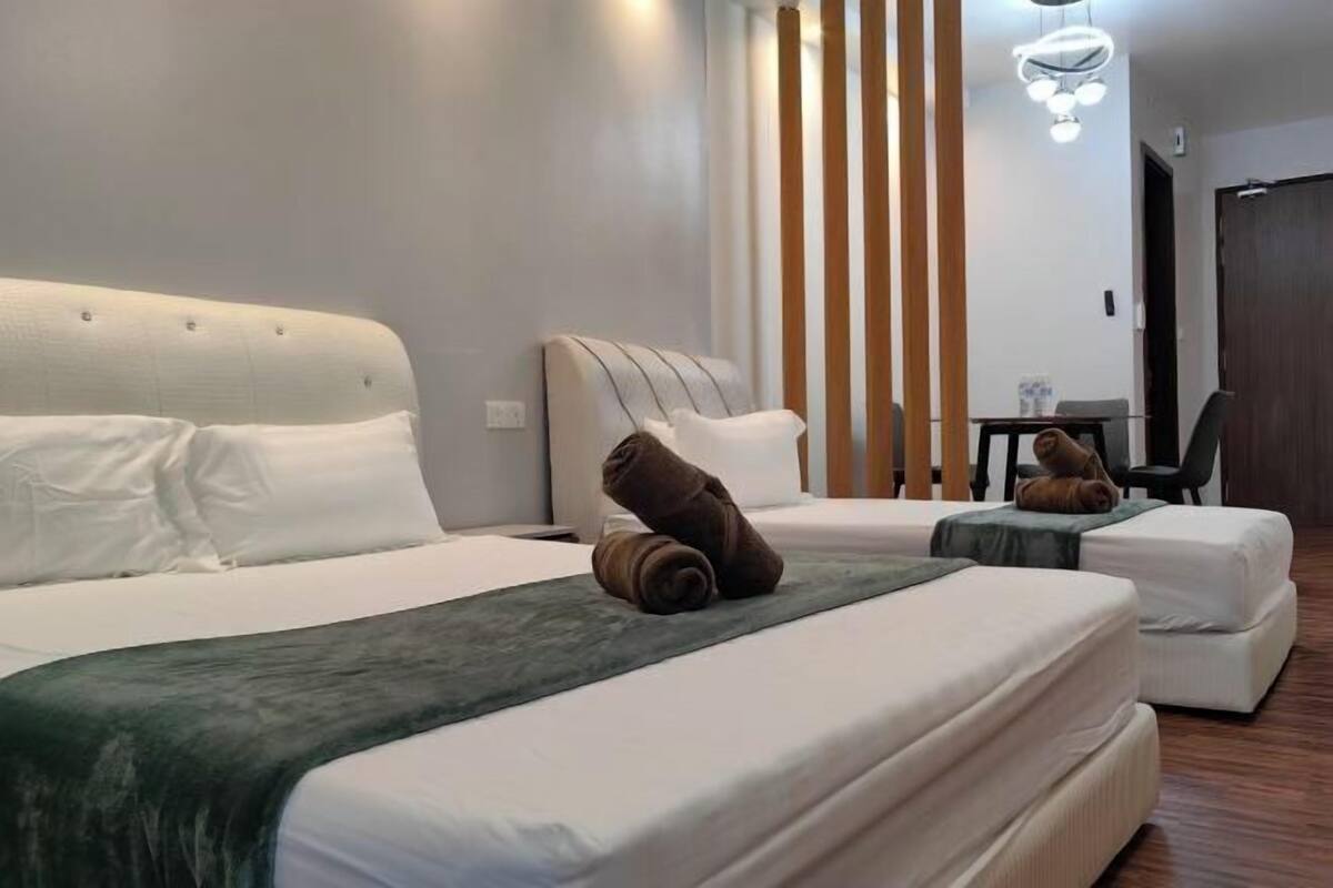A hotel room with a bed, a chair, a small table, and a mirror.