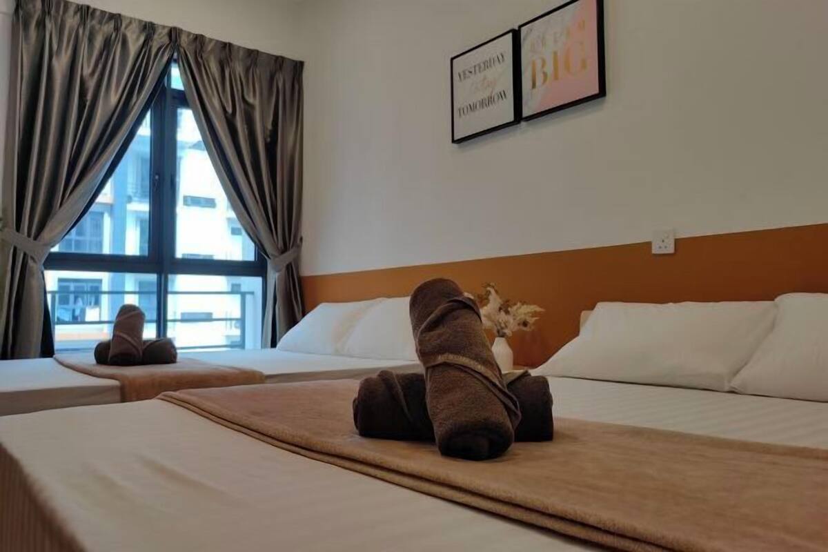 A hotel room with two beds, a large window with curtains, a wall-mounted artwork, and a towel on the bed.