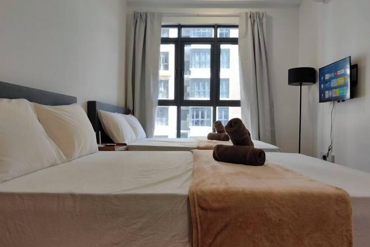 A hotel room with two beds, a TV, and a window with curtains.