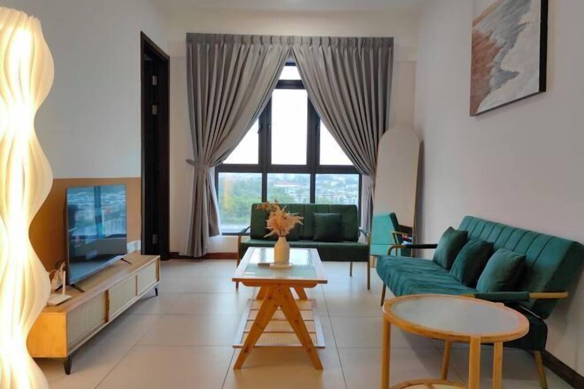 A living room with a TV, sofa, coffee table, and a window with curtains.