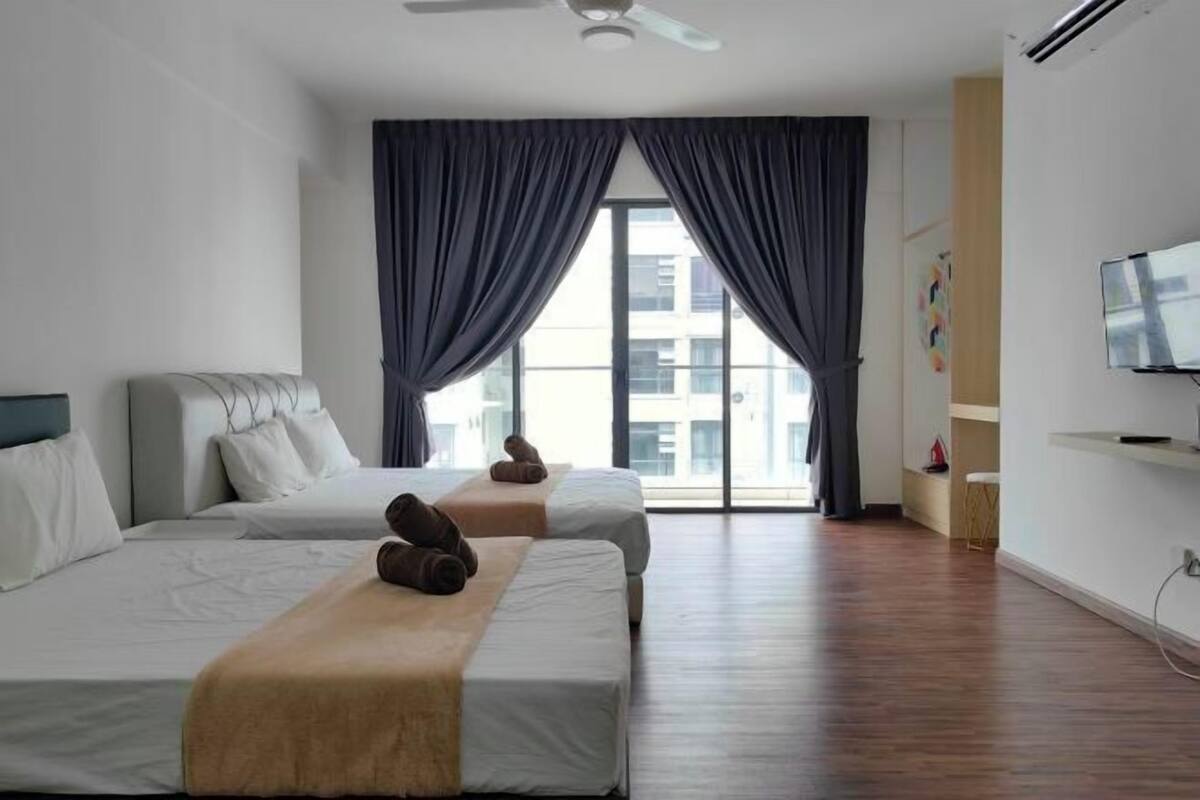 A hotel room with two beds, a TV, and a large window with curtains.