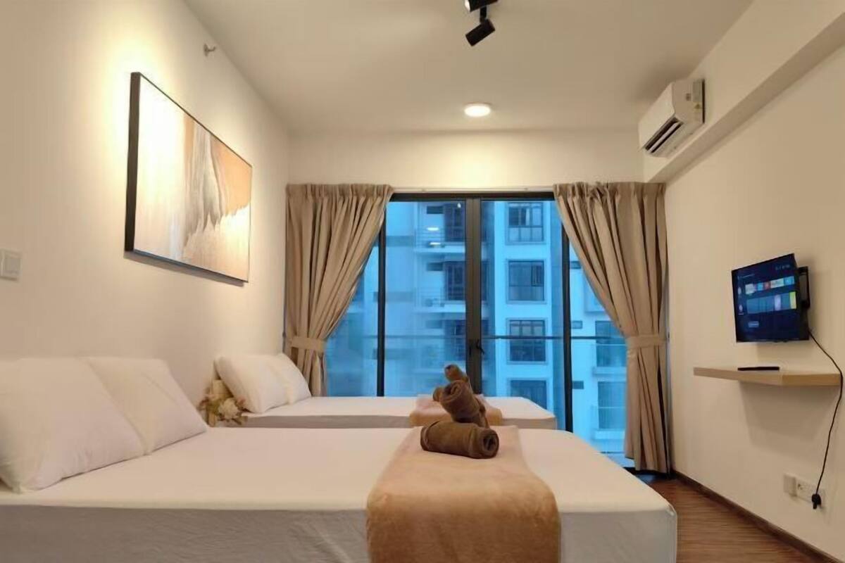 A hotel room with two beds, a TV, and a window with curtains.
