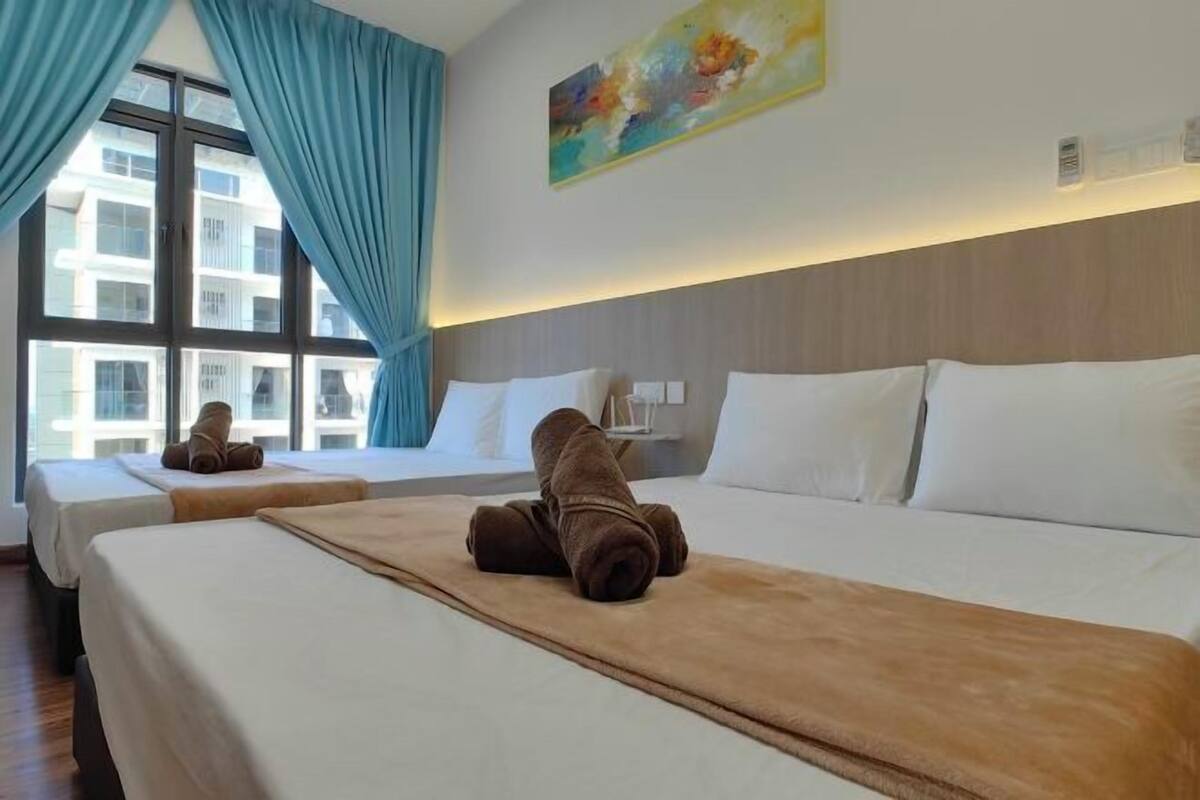 A hotel room with two beds, a large window with curtains, a painting on the wall, and a view of buildings outside.