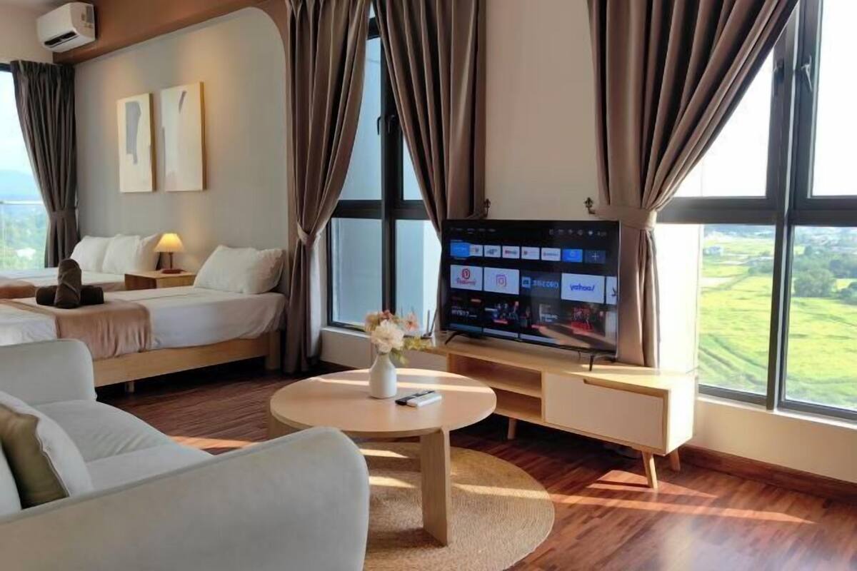 A hotel room with a bed, a sofa, a TV, and a large window.