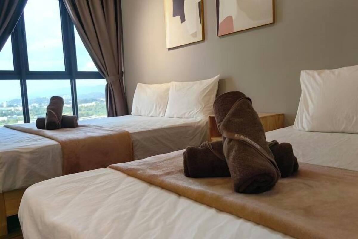 A hotel room with two beds, a view through large windows, and artwork on the wall.