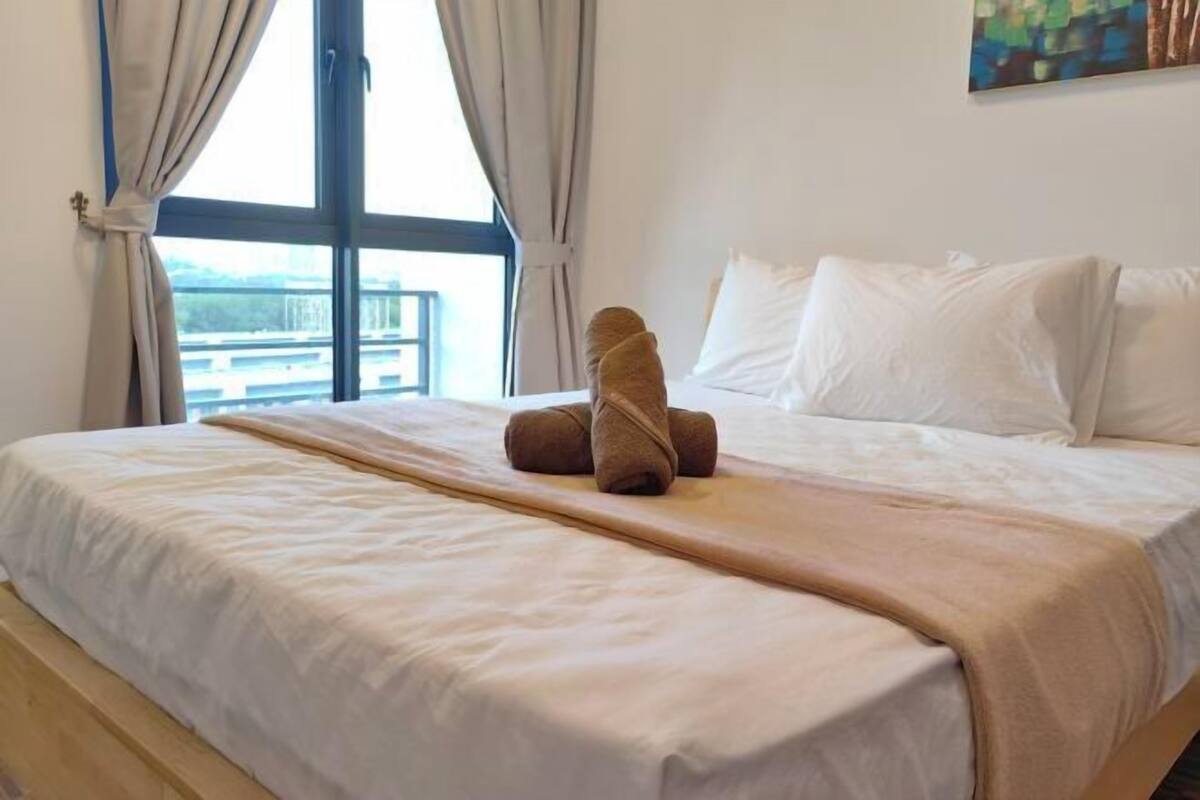 A hotel room with a bed, a window with curtains, and a painting on the wall.