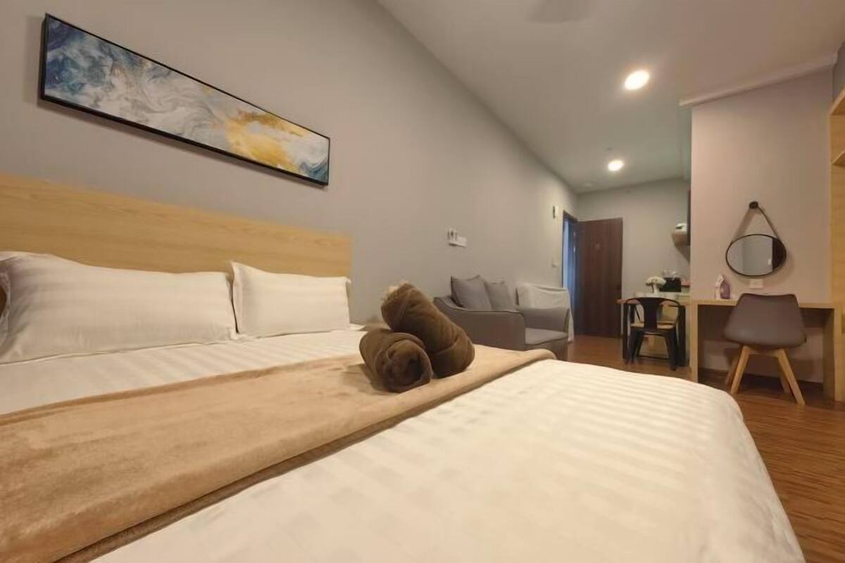 A hotel room with a bed, a desk, a chair, a mirror, and a painting on the wall.