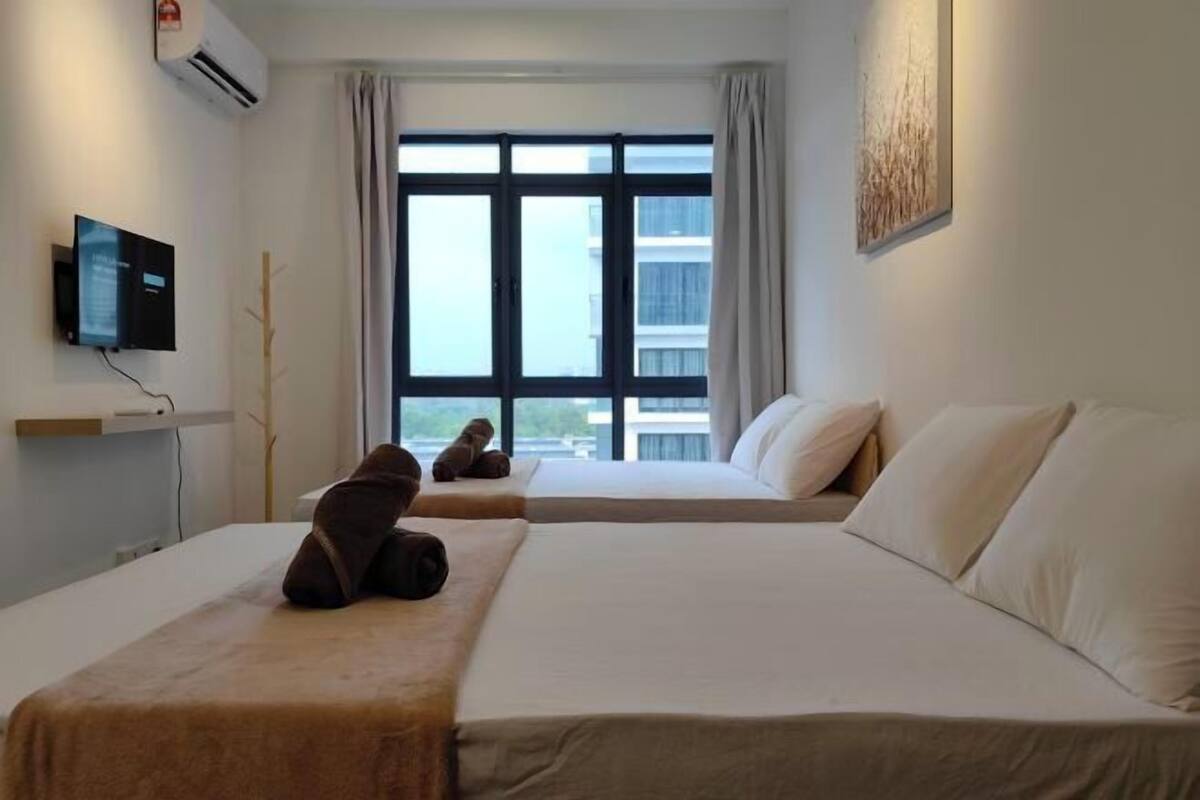 A hotel room with two beds, a TV, an air conditioner, and a large window with curtains.