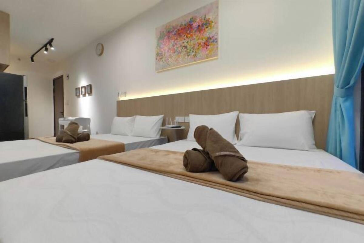 A hotel room with two beds, a large painting on the wall, and a blue curtain.