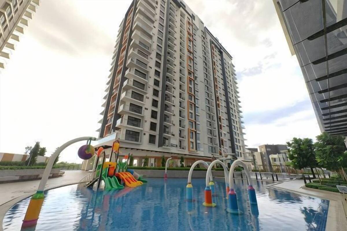 A swimming pool with a slide and water toys, surrounded by tall residential buildings.
