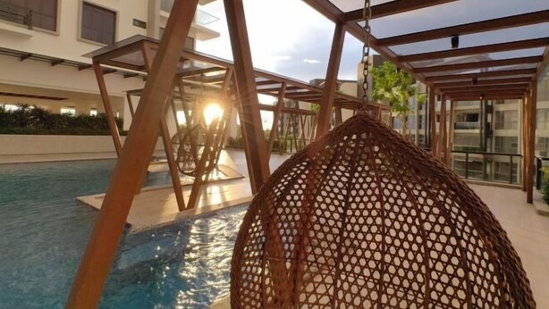 Area piscina con una sedia a dondolo e una pergola.