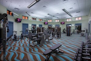 A gym with various exercise equipment, including treadmills, weight machines, and free weights.
