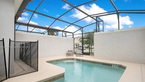 A swimming pool with a glass ceiling, a chair, and a fence.