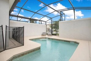 A swimming pool with a glass ceiling, a chair, and a fence.