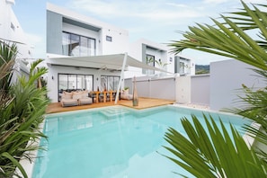 A modern poolside area with a seating arrangement and a covered patio.