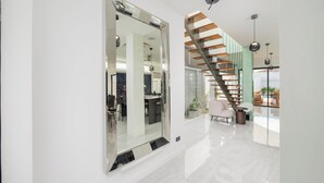Ein modernes Interieur mit einem großen Spiegel, einer Treppe und einem Essbereich.