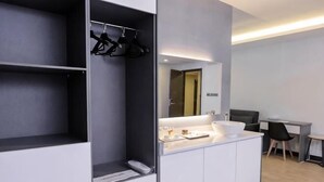 A modern hotel room with a built-in wardrobe, a vanity with a mirror, and a desk area. - Semporna Lighthouse Hotel (Semporna)