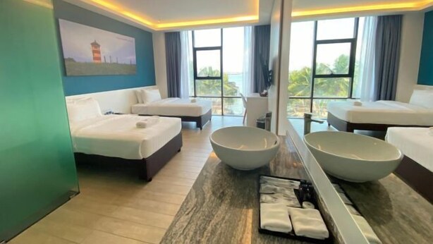 A hotel room with two beds, a large mirror, a bowl, and a tray with towels. - Semporna Lighthouse Hotel (Semporna)