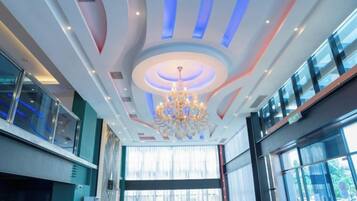 A hotel lobby with a modern chandelier, large windows, and a curved ceiling design.
