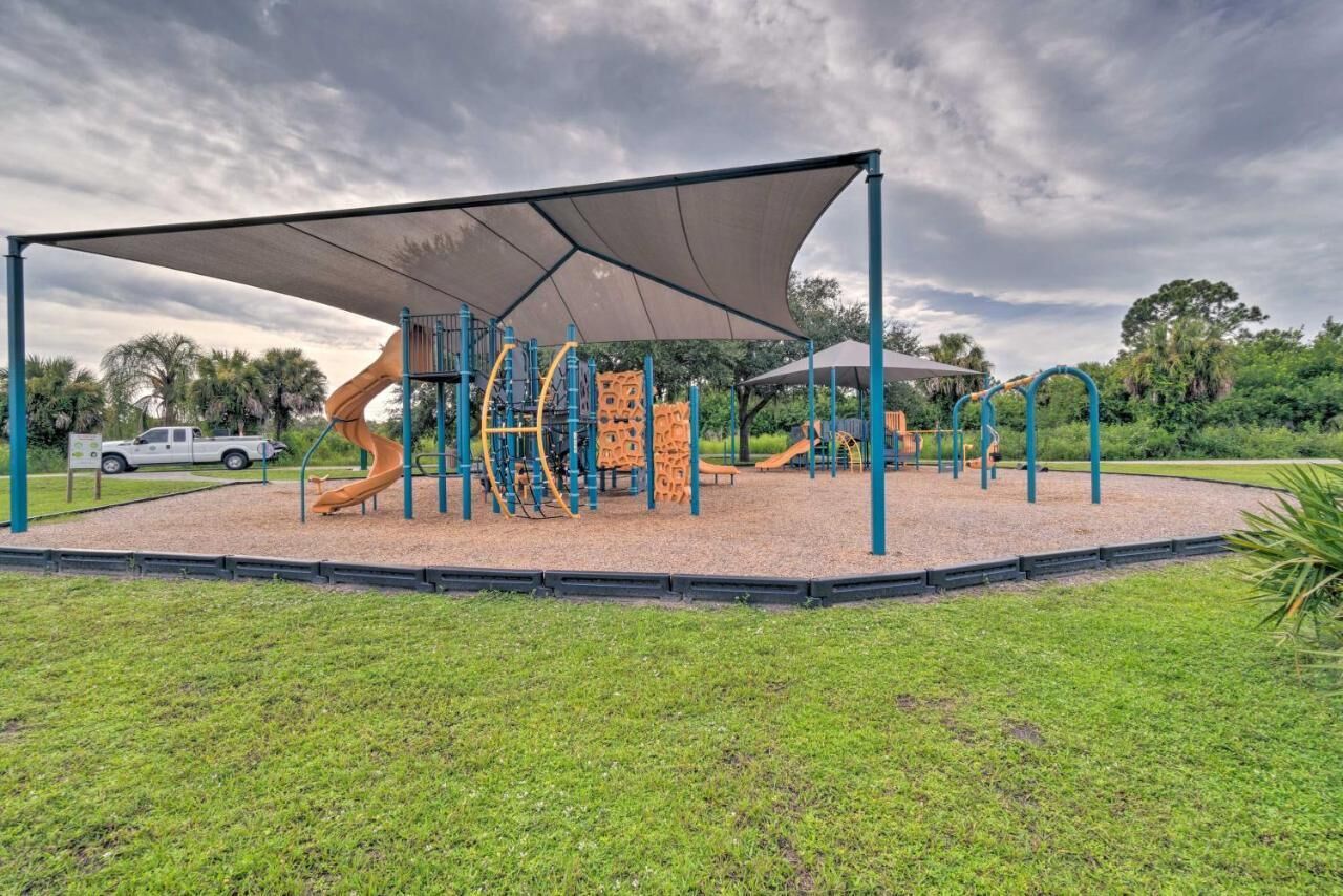 Un parque infantil con diversas estructuras de juego, como toboganes y zonas de escalada, bajo un toldo sombreado.