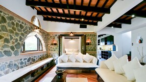 A cozy living room with stone walls, a white sofa, and a wooden bench.