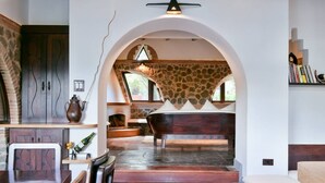 A spacious room with a stone fireplace, a wooden dining table, and a large bathtub.