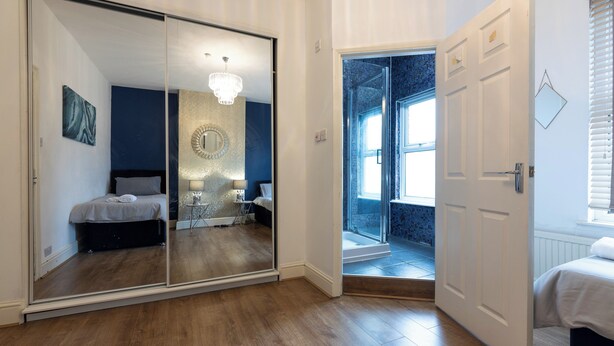 Une chambre à coucher avec un grand miroir, un lit, une table de chevet et un lustre.
