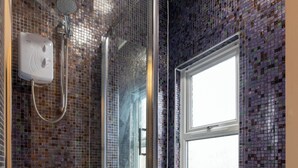 Une salle de bain moderne avec une douche à parois de verre, une fenêtre et un sol carrelé.