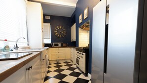 Une cuisine avec un sol à carreaux noirs et blancs, des armoires blanches, un four à micro-ondes et une cuisinière.
