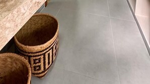 Un baño moderno con un lavamanos ovalado grande, una puerta de madera y un pasillo que conduce a una habitación con cortina.