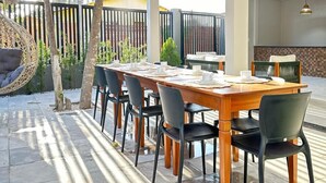 Un patio al aire libre con una mesa y sillas de madera, un colgante de luz y vistas del entorno.