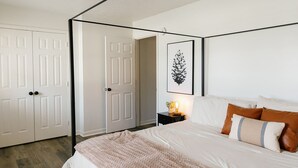 A bedroom with a four-poster bed, a nightstand with a lamp, and a framed artwork on the wall. - "Morning View 2" Cozy Modern Stay - College/Hiking (Berea)