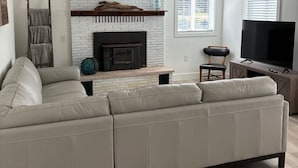 A modern living room with a sectional sofa, a fireplace, a television, and a wooden floor. - Charming 3-bedroom house with WiFi, AC , TESLA Charger in tranquil Lincoln City (Lincoln City)