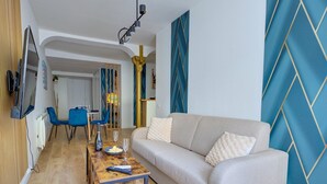 Ein modernes Wohnzimmer mit einer Couch, einem Holztisch und einem an der Wand befestigten Fernseher.