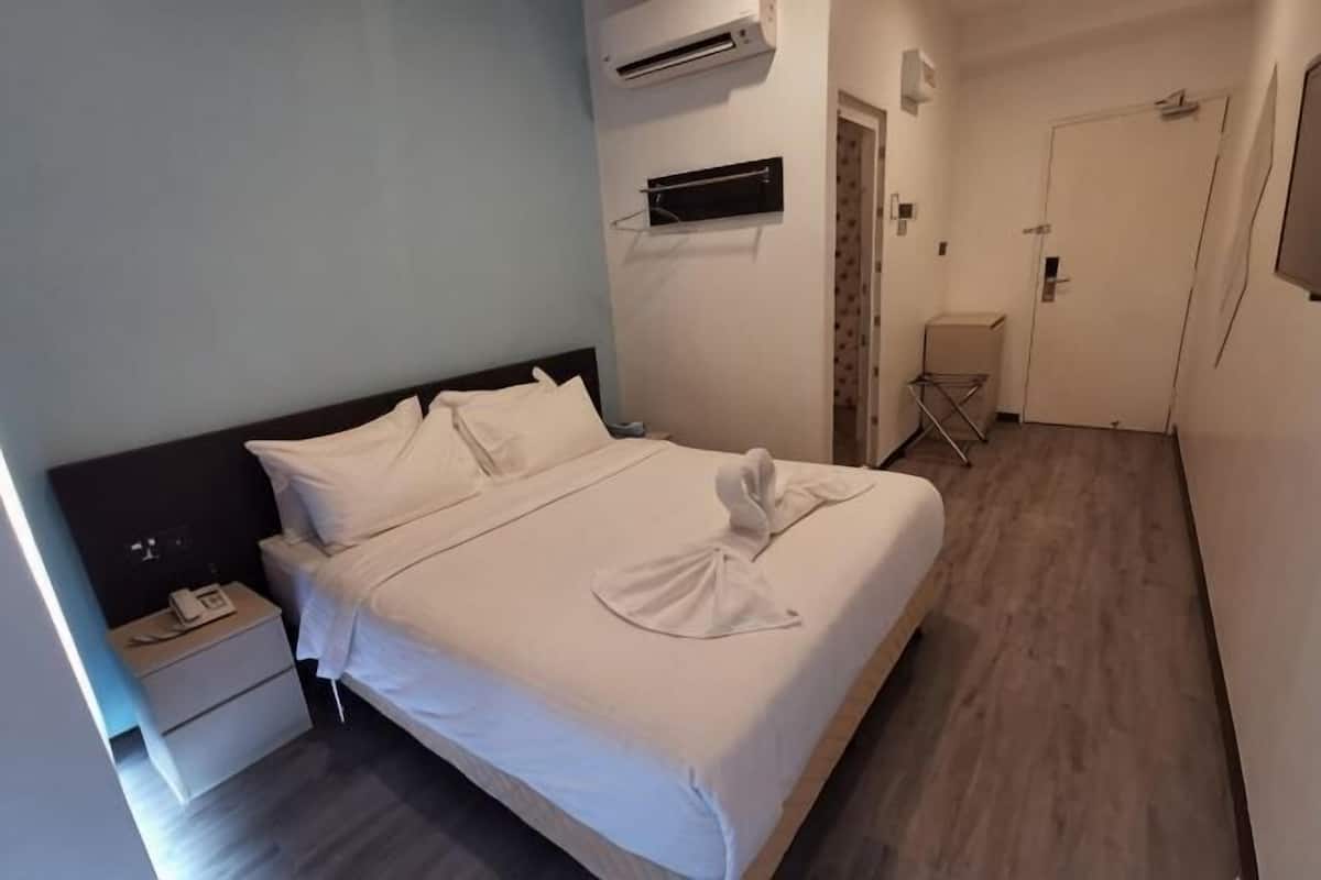 A hotel room with a bed, bedside table, and a small desk with a chair.