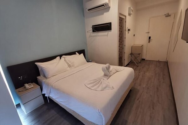 A hotel room with a bed, bedside table, and a small desk with a chair. - TT Dorf Hotel (Taiping) (Tupai)