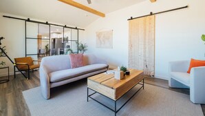 Een moderne woonkamer met een bank, salontafel en stoelen. Er is een schuifdeur en een wereldkaart aan de muur.