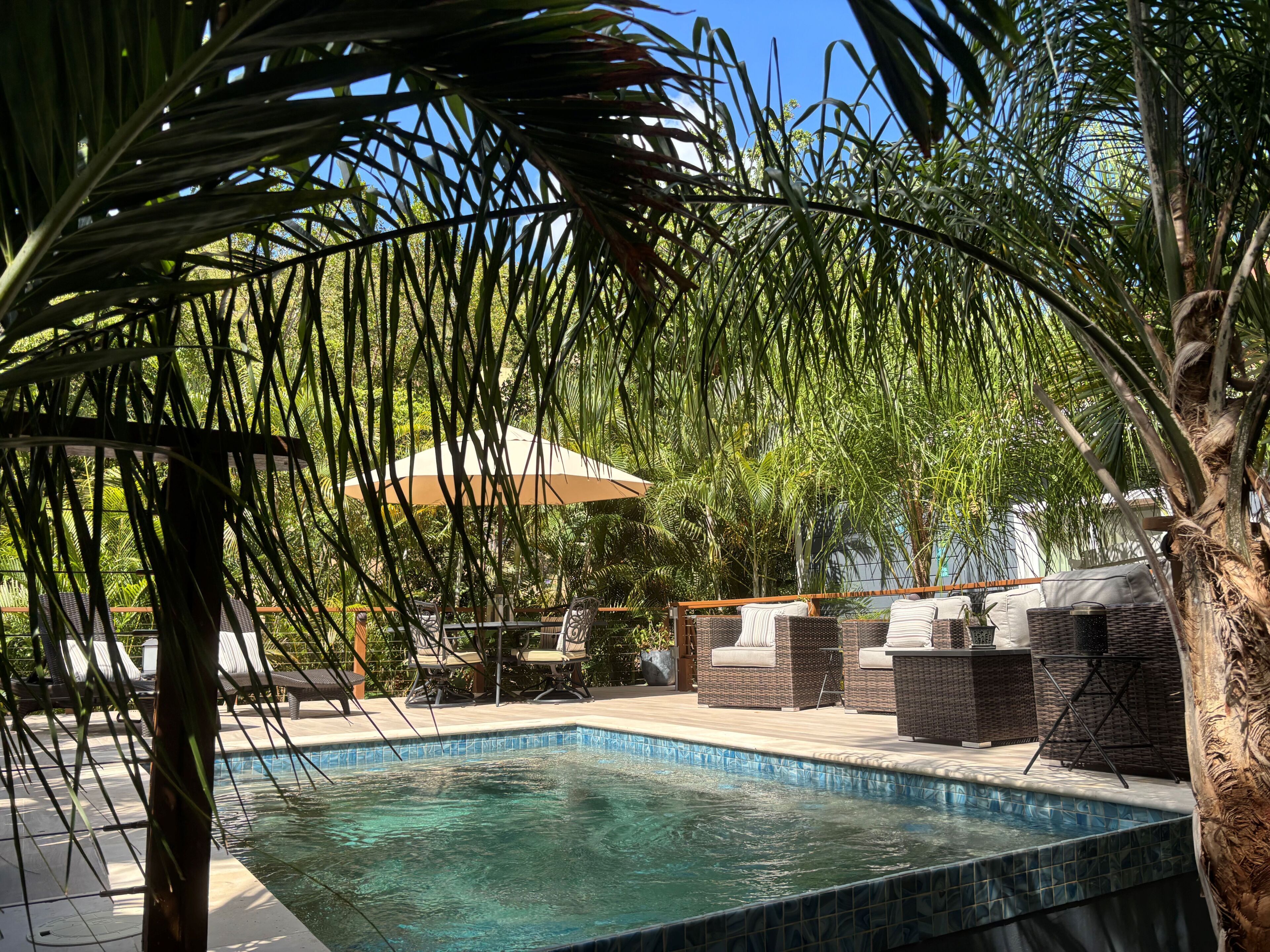 Un área de piscina con sillones reclinables y una pérgola.