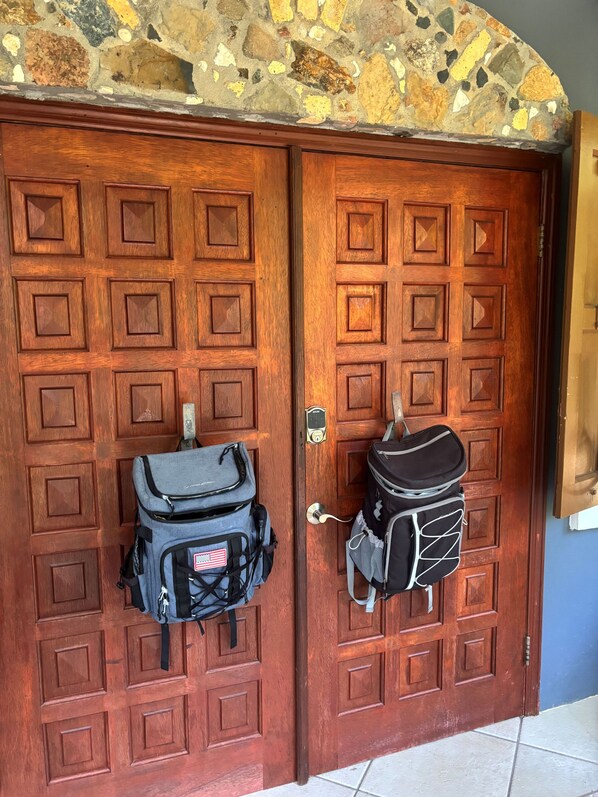 Two wooden doors with a stone arch above, each with a backpack hanging on the door handle. - Sol Cottage Villa 2 BR 2 BA private pool lush landscaping ACs & new generator (Cruz Bay)