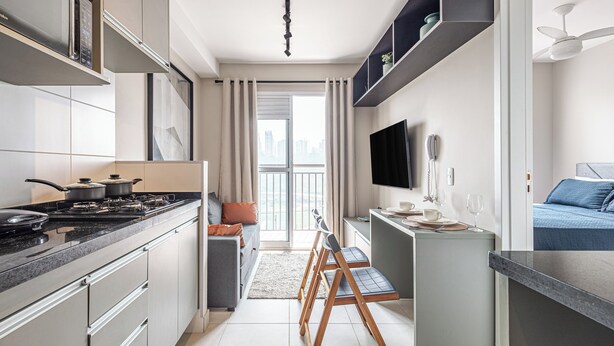 A modern kitchen with a stove, cabinets, and a dining area with chairs.
