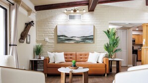 Un salon avec un canapé marron, une table basse ronde en bois et un tableau représentant un paysage marin accroché au mur.