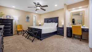Une chambre à coucher comprenant un lit, un bureau, une chaise, une commode, un ventilateur de plafond et un miroir.
