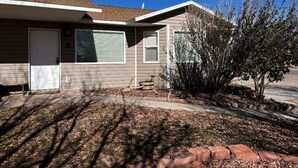 A single-story house with a garage door, a satellite dish, and a small tree in the front yard.