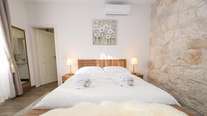 Ett hotellrum med en säng, två sänglampor, en tavla på väggen och en vägg av sten.