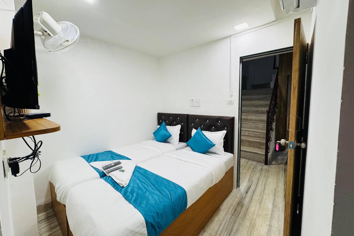A hotel room with a bed, a TV, a desk, and a door.