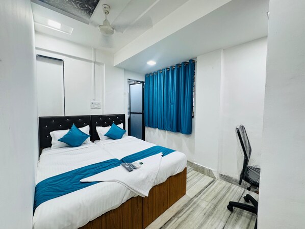 A neatly made bed with a white and blue bedspread, a wooden headboard, and a blue curtain on a window.