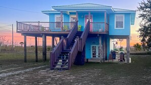 A two-story house with a balcony and a staircase leading to the upper level. - Walk to beach, restaurants, & shopping. Charming, pet-friendly 3BR bungalow.  (Dauphin Island)