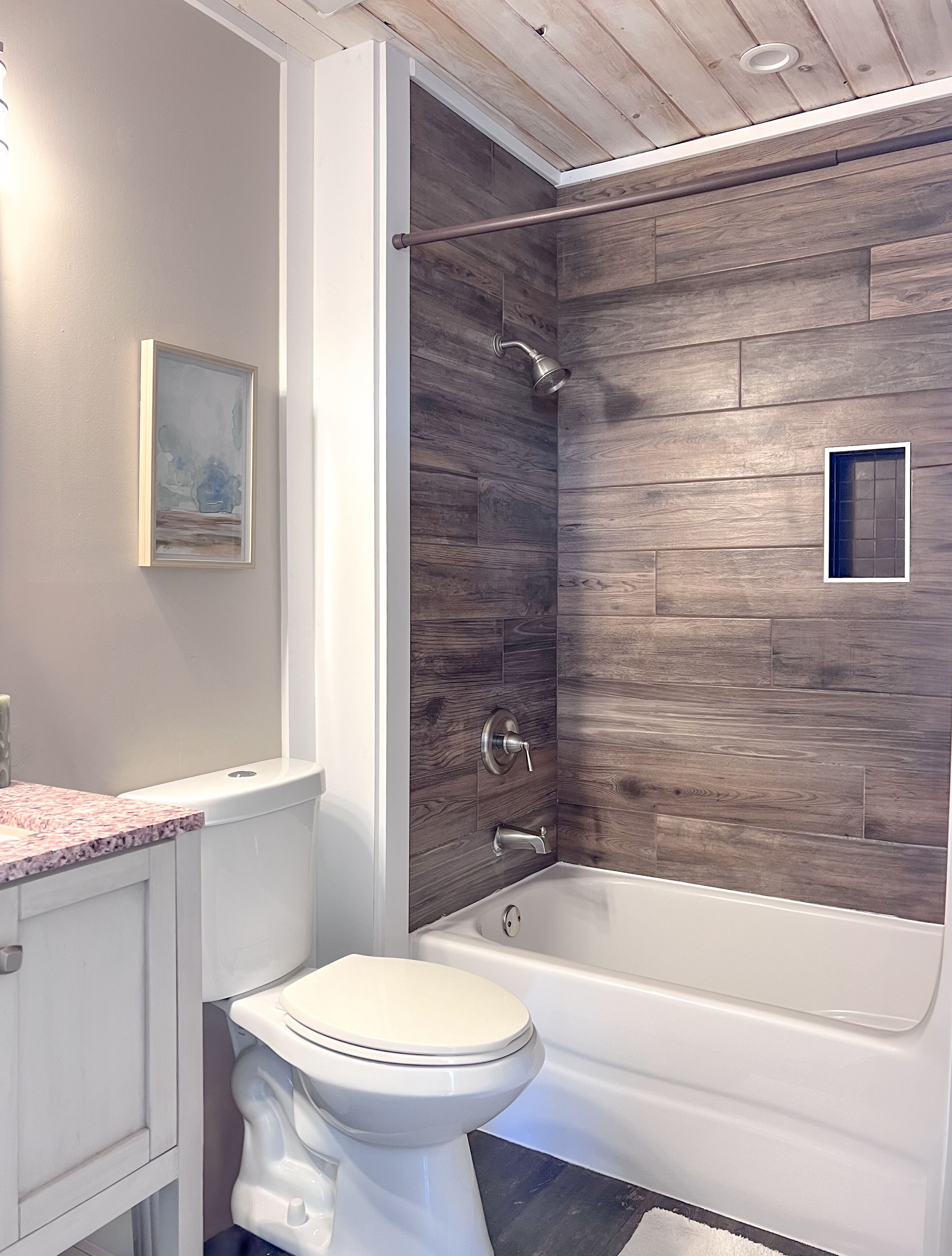 Un baño moderno con pared de madera, una bañera, un inodoro y un lavabo.